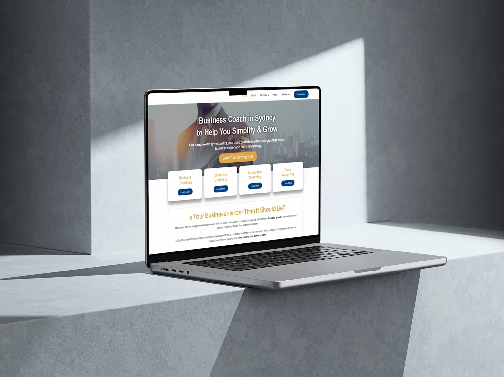 Laptop mockup showing a Stratiks website on screen against a modern concrete background with dramatic lighting.